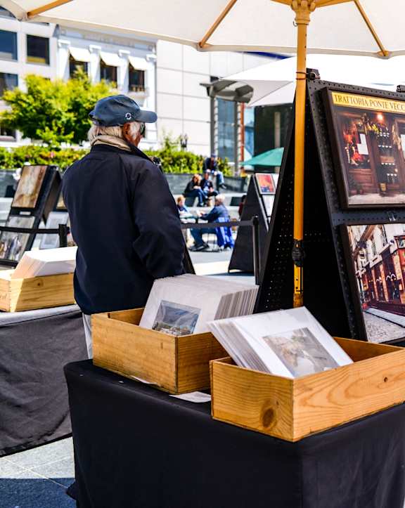 A man is looking at artwork displayed on a table.