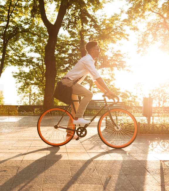 A man riding a bicycle in a park during sunset.