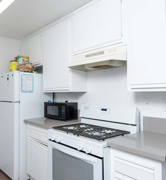 A white kitchen with a fridge, microwave, oven and stove.