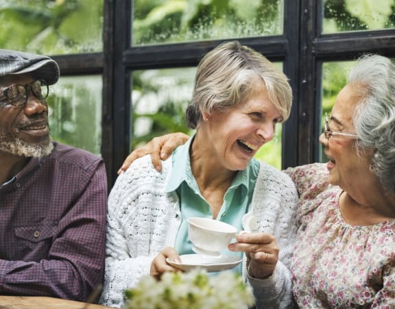 a group of older people sitting at a table with a cup of coffee