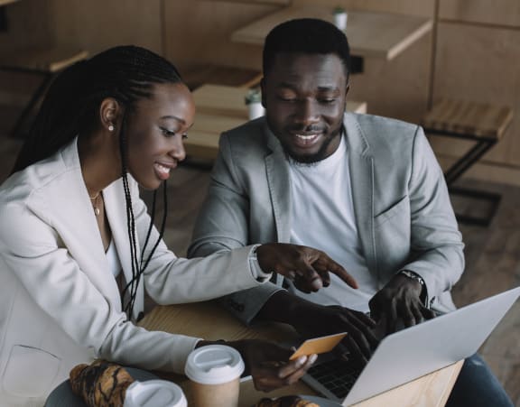 woman and man looking at laptop in a coffee shop together