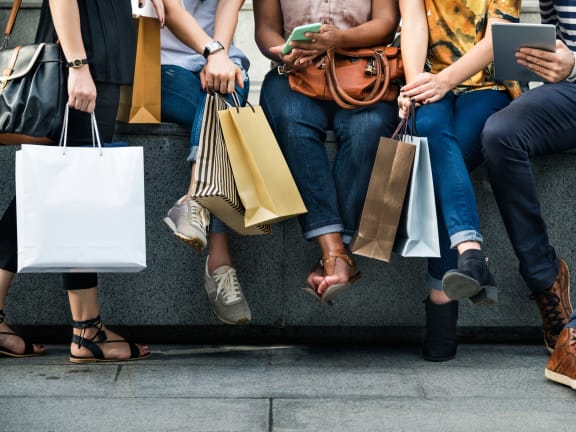 people sitting on a bench holding shopping bags
