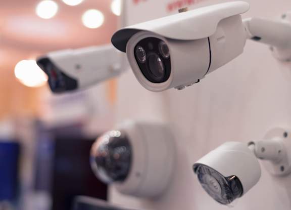 Three white security cameras mounted on a wall.
