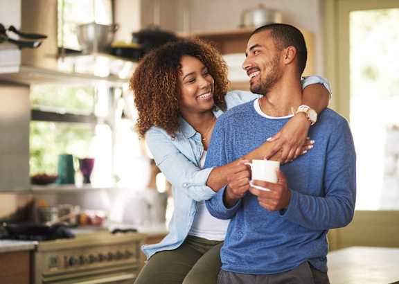 A man and woman are standing in a kitchen, sharing a moment together.