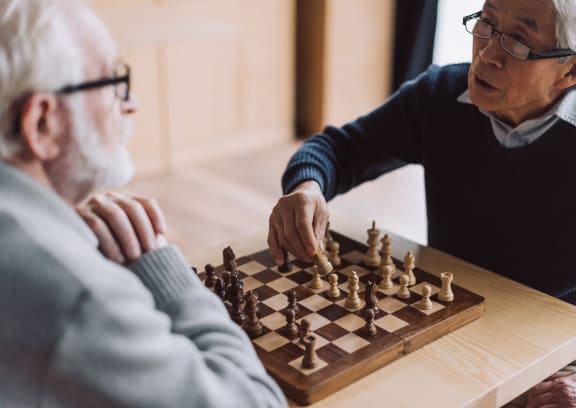 two men playing chess on a wooden board