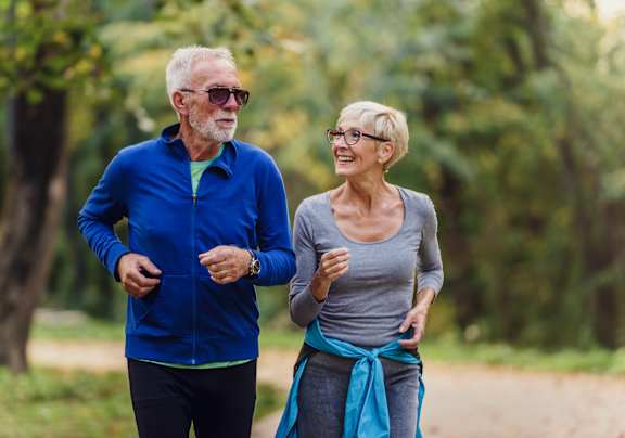 An older couple jogging in a park.