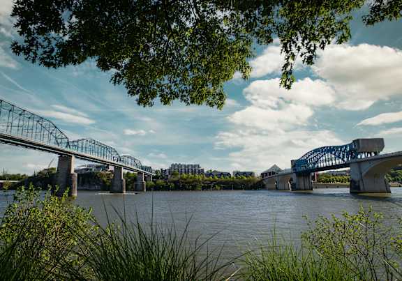 A bridge spans across a river with buildings in the background.