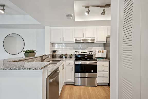 A modern kitchen with a stainless steel oven and white cabinets.