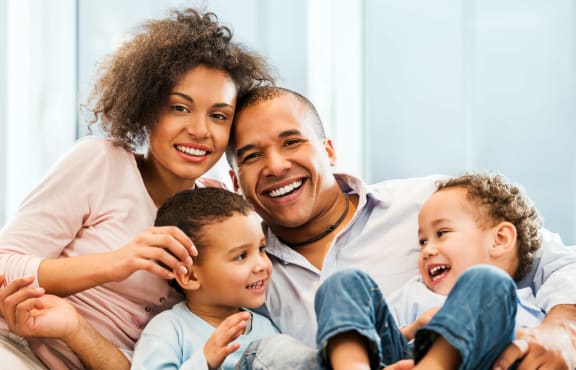 a family sitting on a couch with their three children at Bayville Apartments, Virginia