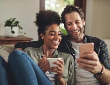 a man and woman sitting on a couch looking at a cell phone at Willow Grove Apartments, Sacramento, CA 95825