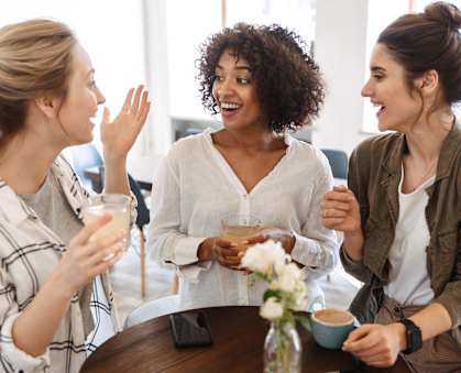 a group of women sitting around a table drinking coffee