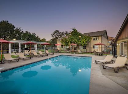 A swimming pool surrounded by lounge chairs and umbrellas.