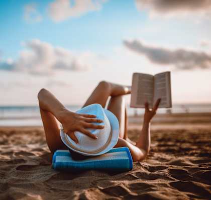 woman laying on the beach reading a book