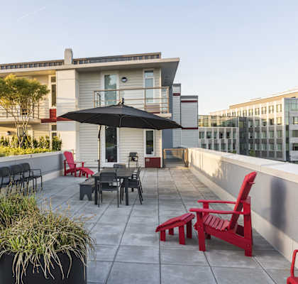 A patio with a table, chairs, and plants.