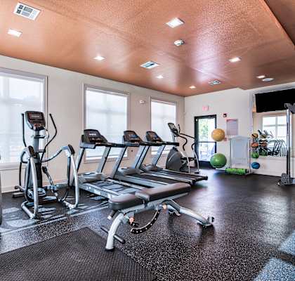 a gym with cardio equipment and windows at Midtown Sam Houston Apartments, Huntsville, TX, 77340