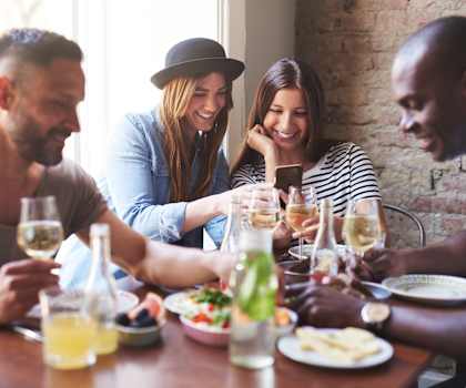 a group of people sitting around a table with food and drinks