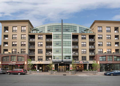 A large building with a glass center and a red car in front of it.