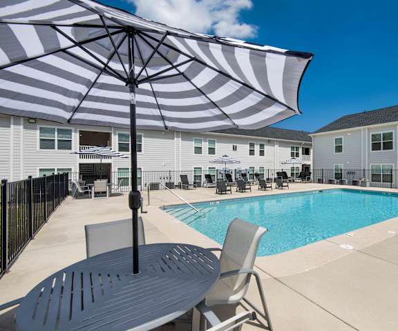 our apartments have a large pool and patio with chairs and an umbrella