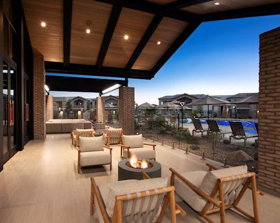 A patio with a fire pit and chairs.