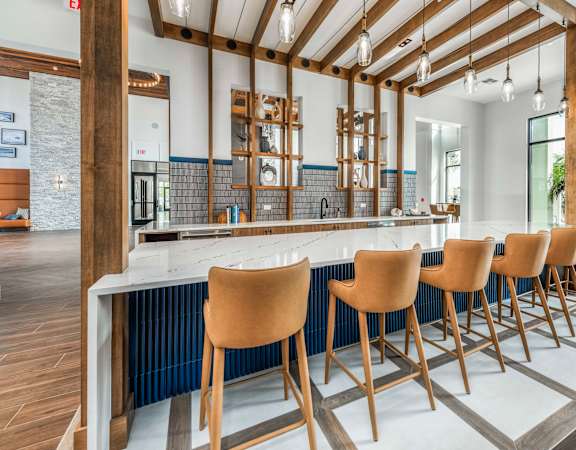A kitchen with a long bar and chairs.