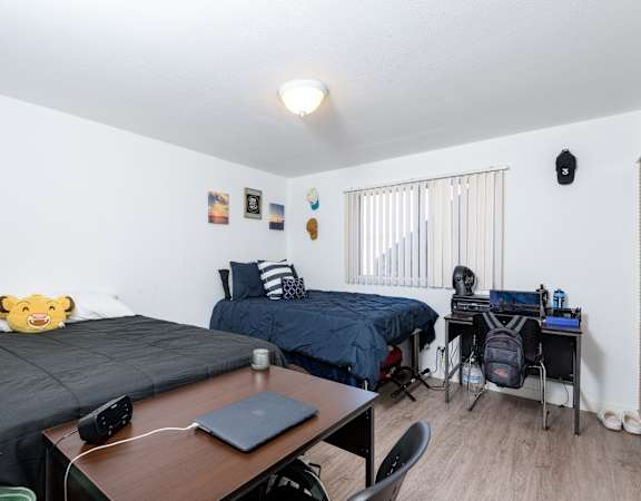 A room with two beds, a desk, and a chair.