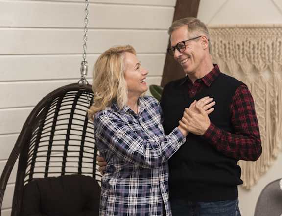 a man and woman standing next to a rocking chair