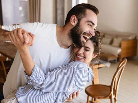 a man and woman laughing while lying on a couch in the living room at Oakridge Apartments, Antioch, California