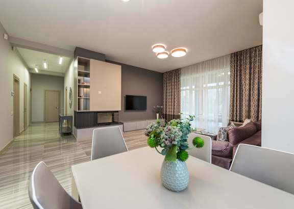 A dining room with a white table and chairs and a television in the corner.