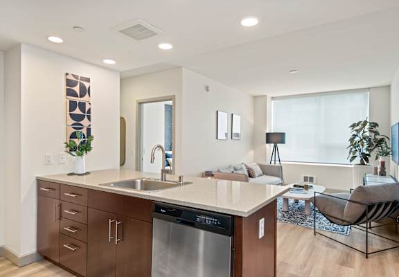 a kitchen with a large center island next to a living room with a couch and a window
