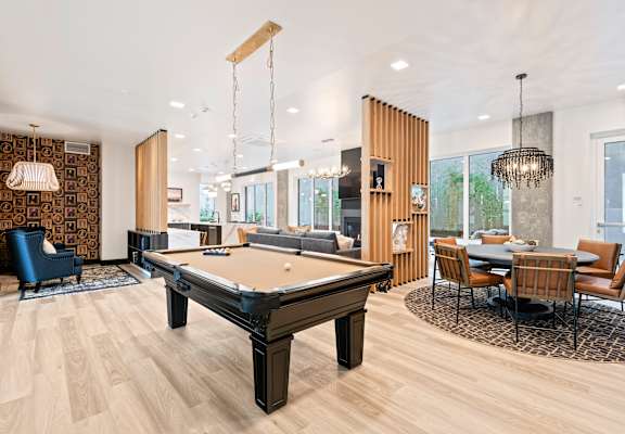 A pool table is in the middle of a room with a dining table and chairs.