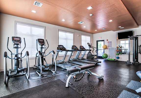 a gym with cardio equipment and windows at Midtown Sam Houston Apartments, Huntsville, TX, 77340