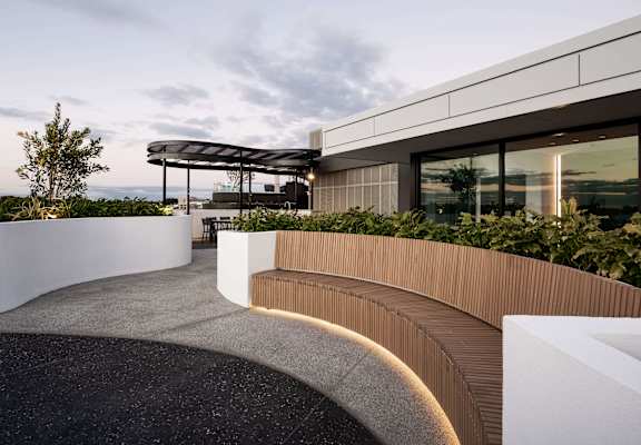 a curved wooden bench in front of a building