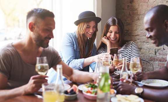 a group of people sitting around a table with food and drinks