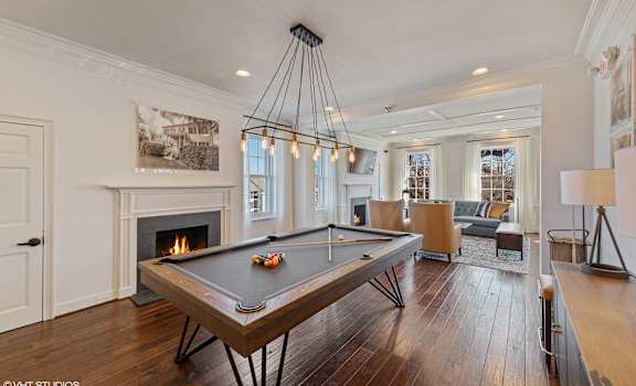 A pool table is in the middle of a room with a fireplace and a picture on the wall.