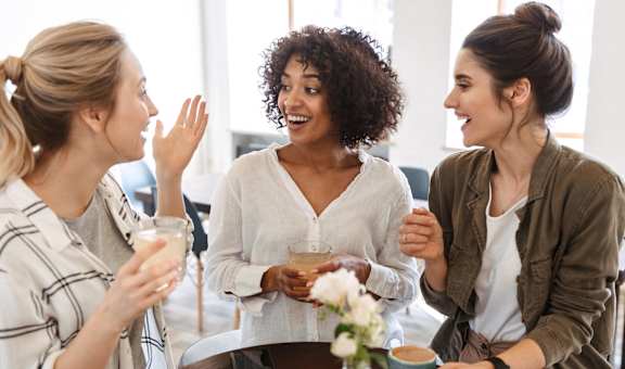 a group of women sitting around a table drinking coffee