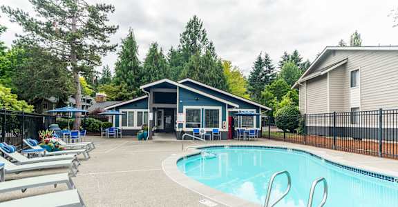 A pool with a slide and a house in the background.
