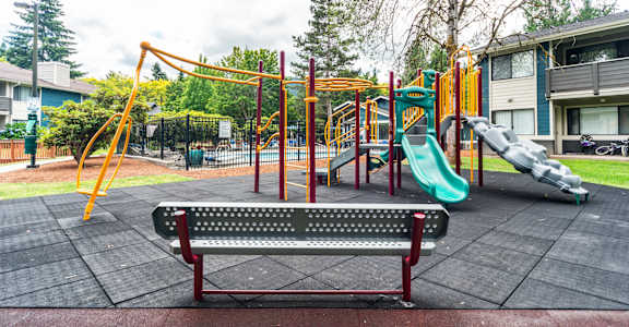 A playground with a red bench and a green slide.