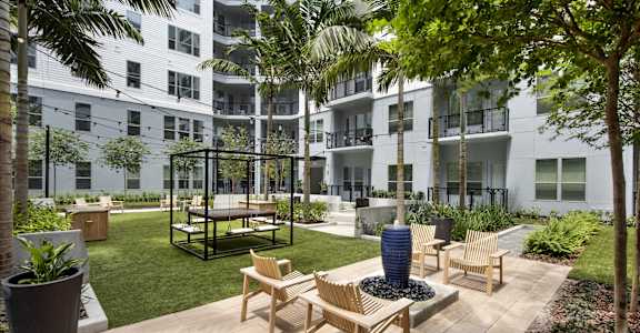 an outdoor patio with chairs and a blue vase in front of an apartment building