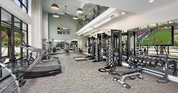 a gym with cardio machines and weights and a large tv
