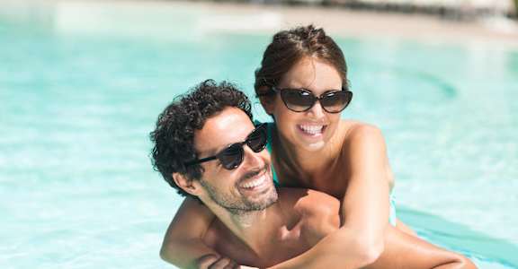 A man and a woman are enjoying their time in a swimming pool.