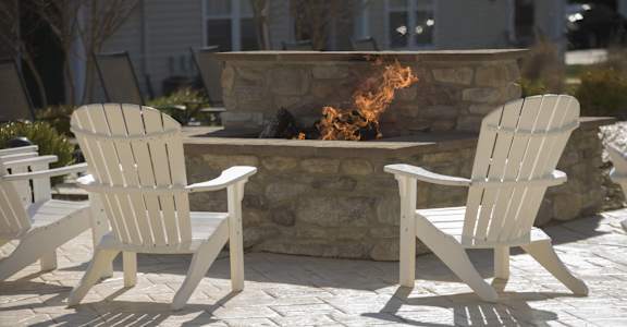 a group of white wooden chairs in front of a fire pit