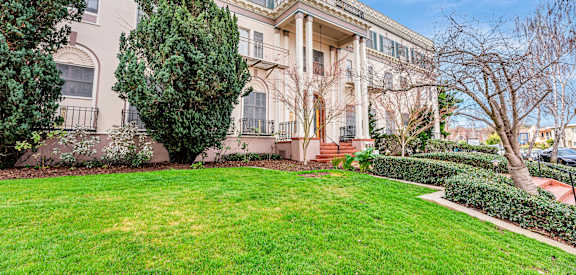 A large, well-maintained lawn in front of a two-story building with a balcony.