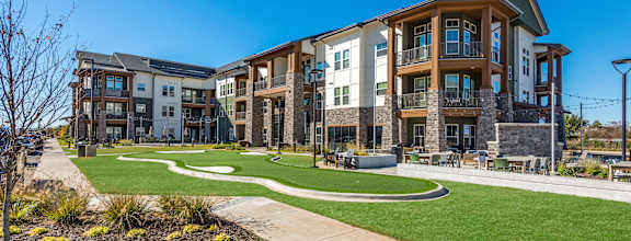 A modern apartment complex with a well-maintained lawn and landscaping.