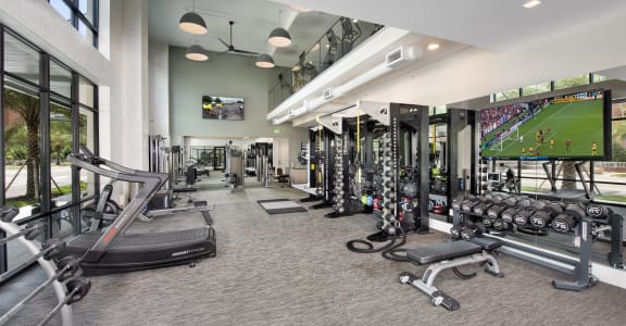 a gym with cardio machines and weights and a large tv