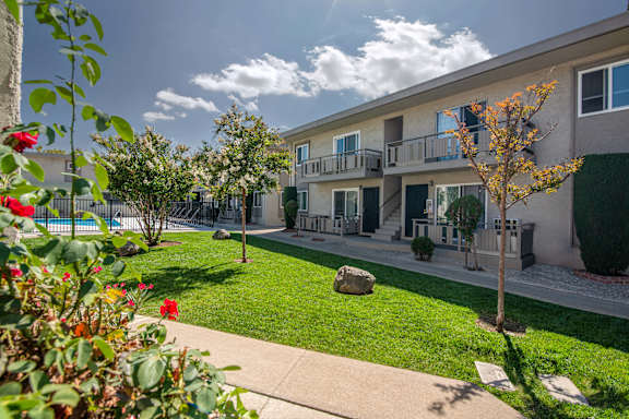 an exterior view of a building with a lawn and a pool