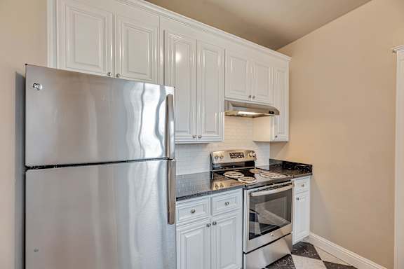 a kitchen with white cabinets and a stove and sink
