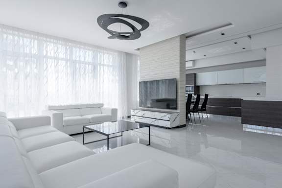A modern living room with white furniture and a large window.