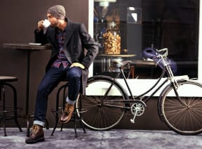 a man sitting on a stool next to a bicycle