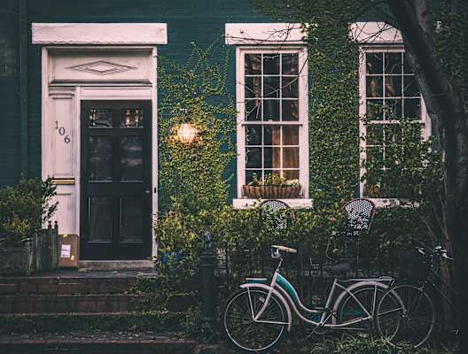 A bicycle is parked in front of a house with a door numbered 106.