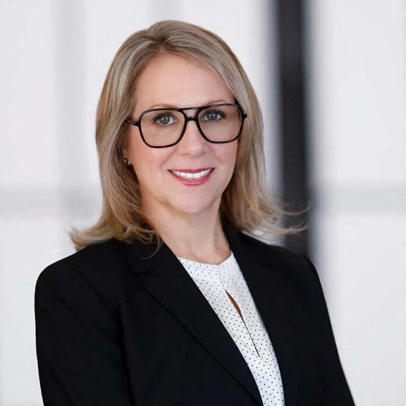 a woman wearing glasses and a black suit